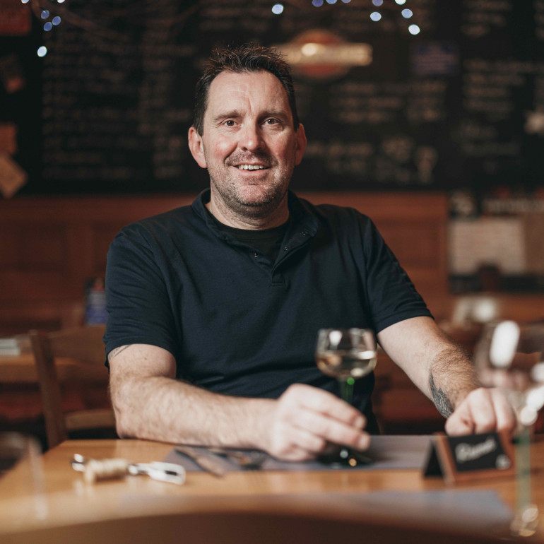 Der Wirt Helmut mit einem Glas Weißwein