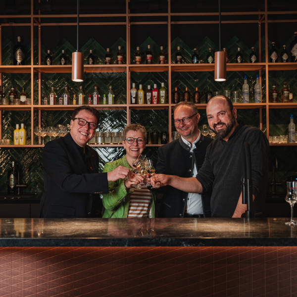 Vier Personen stoßen mit Schnapsgläsern in der Bar der Bimmerle-Gruppe im Schwarzwald an