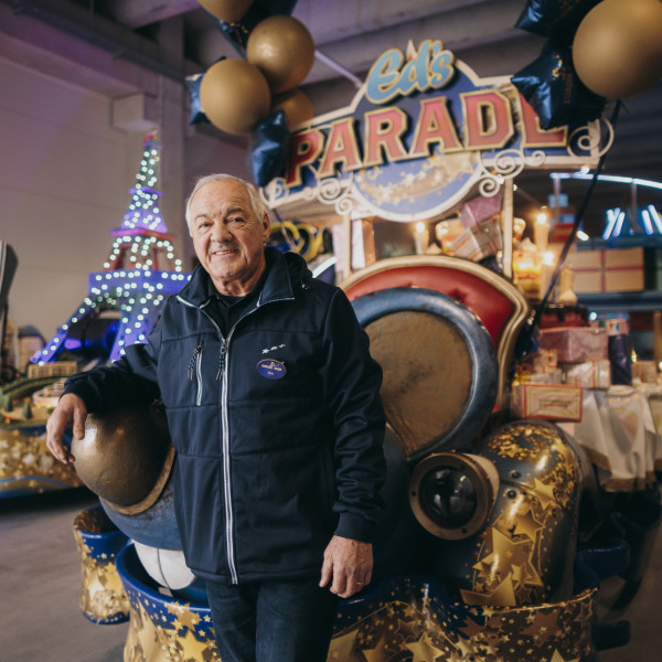 Wagenmeister lehnt sich lächelnd an einen Paradewagen in einer Werkstatt im Europapark