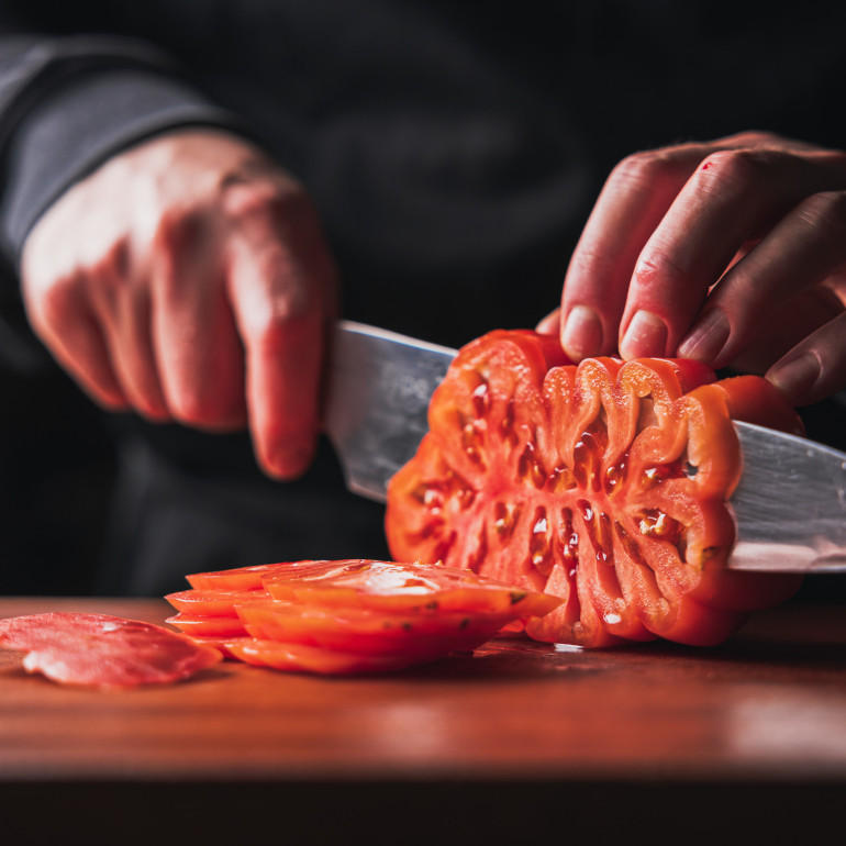 Person schneidet Ochsenherztomate