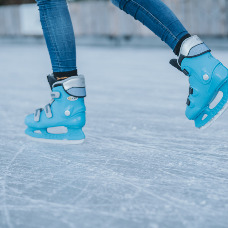Zwei Füße in Schlittschuhen gleiten über eine Eisbahn